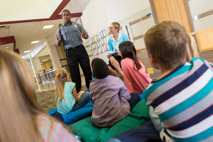Police or school security officer speaking to young students